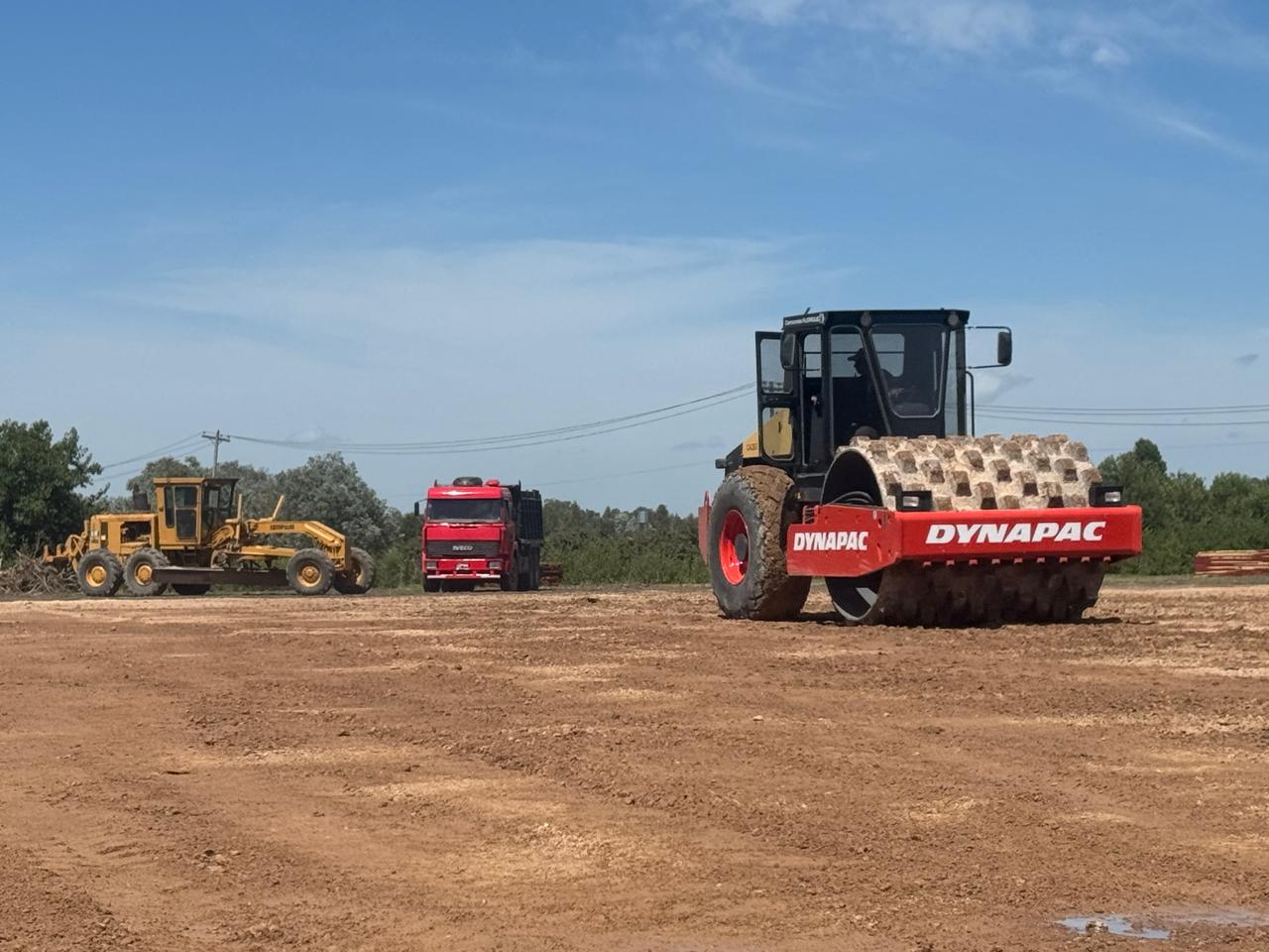 Rodillo compactador Dynapac y motoniveladora trabajando sobre un terreno de tierra